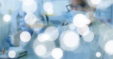 Parlak örtülü laboratuvar araştırmacılarının kaldırdığı ve kehribar matarası dönen berraklığı denetlediği. Bilim, deney, yenilik, kesinlik, işbirliği, araştırma, laboratuvar