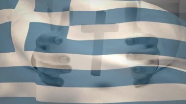 Erkek elleri Latin haçı tutarken, Yunan bayrağı inancıyla solup el sallıyor. Ruhani, adanmışlık, umut, huzur, sembolizm, inanç, vatanseverlik.