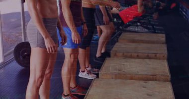 Fitness grubu kamera tutuşu sırasında çömelirken ölçü güncellemeli halterlerle halterlere basıyor. Atletizm, takım çalışması, güç, eğitim, hareket, dayanıklılık, spor