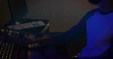 Ses mühendisi stüdyo penceresinden bakıyor, ses kaydedicileri ayarlıyor ve bandı temiz karışıma ayarlıyor. Stüdyo, ses, karıştırma, işbirliği, müzik, profesyonel, mühendisler