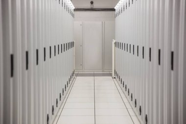 Düz tasarım raflar, zemin panelleri, kablo tepsileri ve boş panelle veri merkezi koridorunu gösteriyor. Teknoloji, altyapı, endüstriyel, modern, bağlantı, ağ, dijital