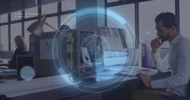 Thinking man reviewing screen at right desk in open plan office, with file folders, copy space. Collaboration, productivity, workspace, modern, technology, teamwork, openness