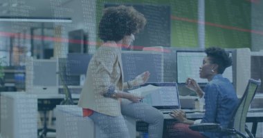 Collaborating women in business attire discussing code on monitors at open plan office, with tablet. Professional, teamwork, innovation, modern, technology, corporate, productivity