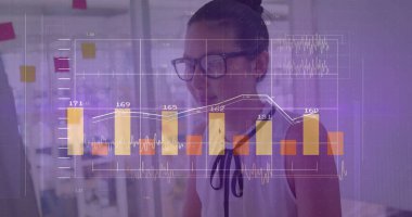 Woman wearing glasses and sleeveless blouse reviewing chart overlay on laptop at desk, sticky notes. Businesswoman, data visualization, modern workspace, corporate, analytics, technology, professional