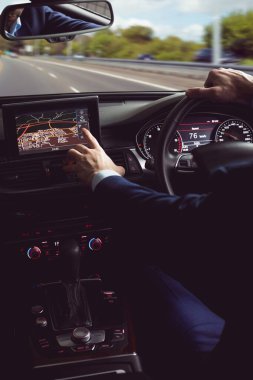 Man wearing business attire is driving flat design car on highway with touchscreen gauges. Automobile, transportation, technology, road trip, motion, travel, luxury