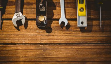 Tools including wrench, plane, level and screwdriver are sitting on wooden workbench in flat design. Craftsmanship, hardware, manual, construction, industrial, repair, woodworking