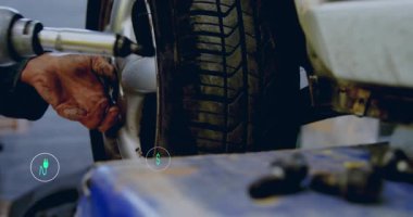 Tekerlek üzerinde pnömatik anahtar kullanan tamircinin eli, enerji metrik simgeleri üretirken fındıkları gevşetiyor. Otomotiv, onarım, teknoloji, sürdürülebilirlik, enerji, yenilik, bakım