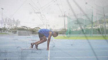 Sprinter crouching at starting blocks on track, shifting forward and driving explosive sprint start. Athlete, competition, motion, agility, endurance, training, athleticism