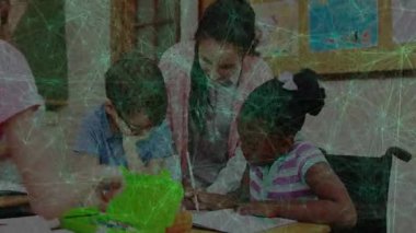 Öğretmenim tekerlekli sandalyedeki öğrencinin el yazısına eğiliyor. Eğitmen, akıl hocalığı, erişilebilirlik, öğrenme, teşvik, ilham, odaklanma