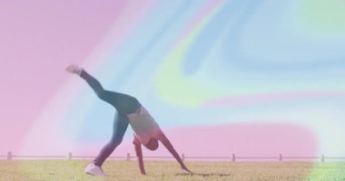 Çocuk ağırlığını sağ ayağa veriyor ve çitle çevrilmiş çimenlik spor antrenmanında takla atmaya başlıyor. Atletik, hareketli, açık havada, enerjik, aktif, boş, dinamik