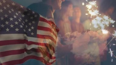 Arkadaşların verandada bayrak altında kıvılcımlar çakan havai fişekler getirip kutlama yapıyorlar. Vatansever, kutlama, yoldaşlık, parlayan, açık hava, alacakaranlık, birlik