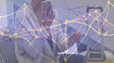 Telefonları dinleyen ve bağlantı için çağrı yapan bir kadın. Bavulun başında ağ kaplamalı oturuyor. Seyahat, havaalanı, iletişim, teknoloji, eğlence, hareketlilik, yaşam tarzı