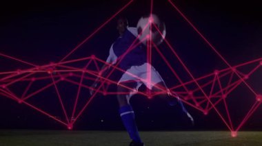 Futbolcu topu alıyor sonra gece sahasında vuruyor, kırmızı ağ spor teknolojisini örtüyor. Sporcu, hareket, dijital, spor, eğitim, performans, fütüristik