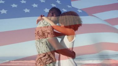 Kumlu sahilde kucaklaşan çift, pazarlamada birbirine doğru sallanarak bayrak sallıyor. Romantizm, şefkat, vatanseverlik, dinginlik, bağlantı, uyum, rahatlık