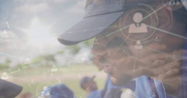 Leaning coach guiding kneeling team wearing blue jerseys on field with network overlays, copy space. Coaching, teamwork, strategy, connectivity, mentorship, collaboration, sportsmanship