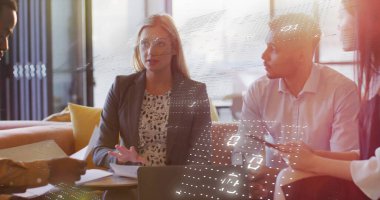 Koyu renk ceketli ve bluzlu bir kadın ofis salonunda diz üstü bilgisayar ve belgelerle el kol hareketi yapıyor. İşbirliği, beyin fırtınası, modernlik, profesyonellik, takım çalışması, yenilikçi, tartışma