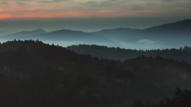 Tepelerin üzerinde parlayan turuncu ışıklar yükselmeye başlıyor. Lens parlaklığı, sisli tepe siluetlerini aydınlatıyor. Manzara, şafak, gün doğumu, dağ, sis, siluet, manzara