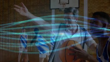 Koç basketbol talimine rehberlik ediyor, kolunu kaldırıyor, neon izleri dönen genç çocuğa pas veriyor. Eğitim, akıl hocalığı, hareket, enerjik, genç, spor, teknoloji