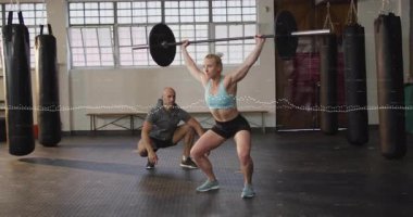 Vücut geliştiren kadın sporcu, spor salonunda sağlık kazancı için animasyon dolgusu ile çömelmeye başlıyor. Güç, zindelik, antrenman, spor, güç, disiplin.