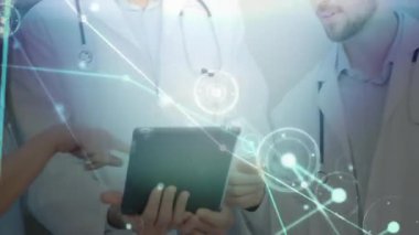 Doktor tıkırdayan tablet hasta bilgilerini, iş birliği yapan veri örtüsünü işaret eden meslektaşları olarak gösteriyor. Tıbbi, işbirliği, yenilik, dijital, sağlık, takım çalışması, fütüristik