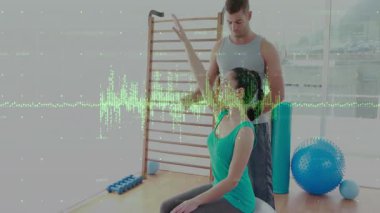 Eğitmen müşterinin omzuna hafifçe vuruyor ve koluyla topa vuruyor. Rehabilitasyon, fizyoterapi, güç, hareket kabiliyeti, teknolojik etkinlik, sağlık, egzersiz