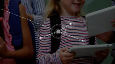 Students looking at tablets activating network graphic linking tablets in classroom collaboration. Technology, education, teamwork, digital, youth, connectivity, innovation