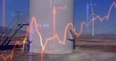 Alan teknisyeni türbin üssüne yaklaşıyor, canlı rüzgar türbini performans grafiğini izliyor. Yenilenebilir, enerji, teknoloji, sanayi, veri, analitik, profesyonel