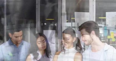 Teknik ekip cam bölmenin yanında toplanıp telefonları kontrol ediyor ve dizüstü bilgisayarın inceleme raporunu inceliyor. İşbirliği, takım çalışması, şirket, üretkenlik, modern iletişim, odaklanma