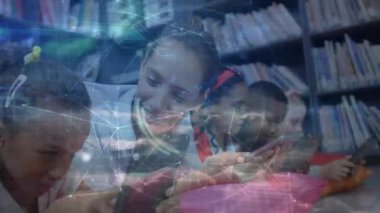 Tableti işaret eden öğretmen ağ başlatılıyor. Kütüphanede öğrenen öğrencilere rehberlik ediyor. Eğitim, işbirliği, dijital, sınıf, öğrenme, yenilik, danışmanlık