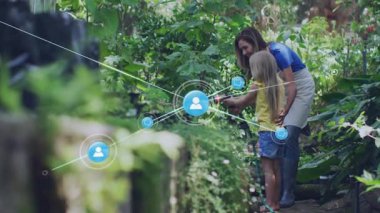 Kızına yol gösteren, hortum sıkan, bitkileri sulayan teknoloji için kullanıcı ikonu üreten bir kadın. Bahçıvanlık, teknoloji, dijital ağ, aile, açık hava, eğitim