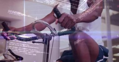 Gidonu kavrayan ve durağan bisikleti pedal çeviren jimnastik kullanıcısı havlu kullanırken veri kaplamasını etkinleştiriyor. Performans, uygunluk, güç, dayanıklılık, dijital, modern, sağlık