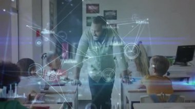 Erkek öğretmen sınıfa giriyor sıralara yaslanıyor, öğrencileri artan veri grafikleriyle meşgul ediyor. Eğitim, işbirliği, yenilik, dijital, teknoloji, gençlik, öğrenim