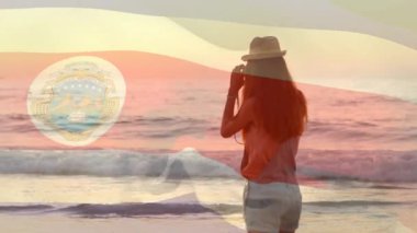 Sahilde kamera kaldıran bir kadın teknoloji gösterisiyle günbatımını yakalıyor. Arkasından sürükleniyor. Deniz manzarası, manzara, sükunet, açık hava, boş zaman, manzara, estetik