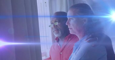 Erkek, destek teklif eden bir kadına sarılıyor, balkon kapısına bakıyor, mercek parlamaları sağlığa süpürüyor. Arkadaşlık, bağlantı, sükunet, zarafet, yansıma, sıcaklık, sükunet.