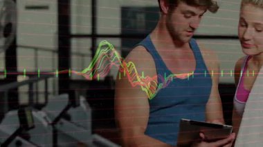 Spor salonunda spor salonu antrenörü ve müşteri tıkırdatma tableti animasyon dalga formlarıyla egzersiz ölçümlerini optimize ediyor. Performans, analitik, işbirliği, teknoloji, motivasyon, sağlık, eğitim