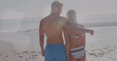 Erkek, kadının sırtına yaslanıyor. Güneşli sahilde pazarlama için sarılıyorlar. Romantizm, bağlantı, dinginlik, açık hava, boş zaman, manzara, sevgi