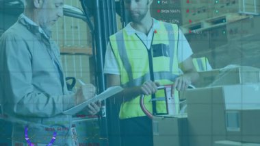 Depo çalışanı palet krikosunu taşırken yönetici panoyu güncelleme ölçümleri olarak not ediyor. Endüstriyel, takım çalışması, üretkenlik, analitik, lojistik, organizasyonel, profesyonel