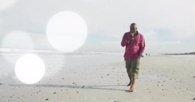 Son sınıf öğrencisi akıllı telefonlara cevap veriyor. Çıplak ayaklı kumlu plajda yürüyor. Lens fişekli teknolojiyi kullanıyor. Emeklilik, dinlenme, rahatlama, kıyı, açık hava, sükunet, sağIık