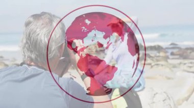 DSLR ile diz çökmüş bir adam görüş açısını yükseltiyor, kayalık kıyılarda poz veren kadını portre için yakalıyor. Manzara, çift, deniz kenarı, boş zaman, doğal, samimi, açık hava