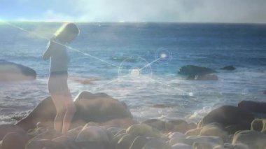 Göğüs sensörü ayarlanıyor, kayalık kıyılarda gezinen kadın veri akışını gösteren düğümler başlatılıyor. Giyilebilir, bağlanabilirlik, teknoloji, açık hava, macera, yenilik, dijital