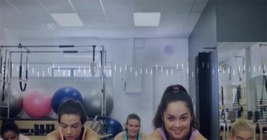 Beş kadın stüdyoya giriyor, paspasları yerleştiriyor ve pilates hareketlerini düzenliyor. Fitness, wellness, collaboration, movement, modern, zindelik, harmony