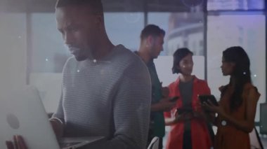 Analiz için gümüş dizüstü bilgisayarda yazan orta yaşlı bir adam, parlayan ağı izleyen meslektaşlar. Teknoloji, işbirliği, yenilik, dijital, takım çalışması, profesyonel, modern