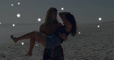 Sahilde çiftlerin buluştuğu bir seyahat reklamı. Parlayan yıldızlar gibi aşk için bir kadını kaldıran bir adam. Romantizm, sahil yürüyüşü, sevgi, günbatımı, bağlantı, sükunet, eğlence