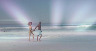 Sahile ayak basan çiftlerin el ele gezip pastel ışıklarla tatile çıktıkları bir seyahat reklamı. Plaj, kıyı şeridi, çift, rahatlama, dinginlik, günbatımı, tropik