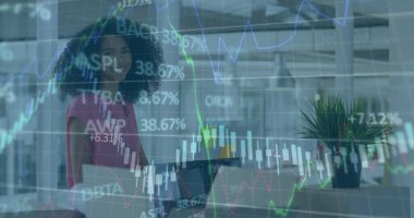 Günümüz açık planlı ofisinde elinde dizüstü bilgisayarla gülümseyen iş kadını, borsa grafikleriyle. Profesyonel, teknoloji, çalışma alanı, yenilik, şirket, üretkenlik, modern