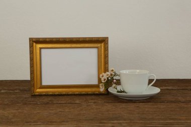 Fotoğraf çerçevesi ve kahve fincanı masanın üstünde, yakın plan.