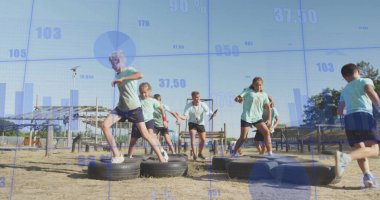 Spor giyimli eğitmen ve çocuklar tekerleklerle parktaki lastik engeli parkından geçiyorlar. Fitness, oyun alanı, açık hava, aktivite, takım çalışması, macera, enerjik