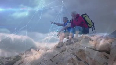 Çift zirveye ulaşıyor, ekipmanları ayarlıyor, ufku işaret ediyor, dijital ağ oluşumunu gözlemliyor. Macera, keşif, tefekkür, yükseklik, bağlantı, yenilik, panoramik
