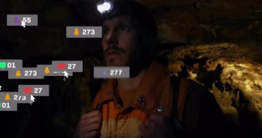 Erkek kaşif farları bağlıyor ve mağara keşiflerine giriyor, sosyal medya bildirimlerini aktifleştiriyor. Macera, keşif, engebeli, teknoloji, dijital arayüz, manzara