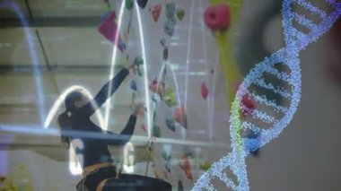 Dişi tırmanıcı, tırmanma duvarına tutunarak nabız ölçer ve sağlık teknisyenleri için dönen sarmal tutar. Macera, fitness, inovasyon, biyomekanik, güç, kararlılık, teknoloji